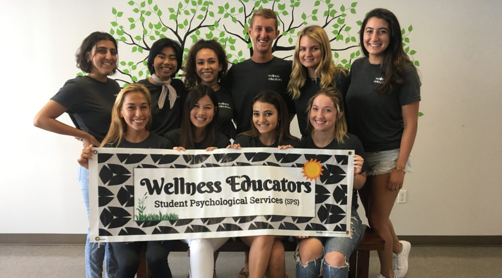 Students standing with Wellness Educators Banner